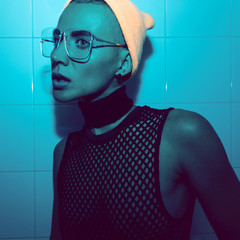 Tomboy Girl in fashion look. Fashion accessory glasses, beanie and choker. Top mesh. Stylish neon...