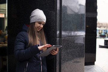 a girl in a jacket stands near the wall