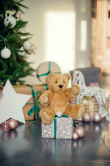 New Year decorations in blue and beige colors. Toy bear, decorative white lanterns and gift boxes under fir-tree. Christmas mood