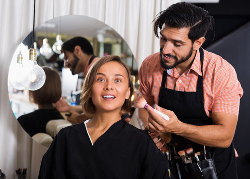 Man makeup specialist applying cosmetics for female