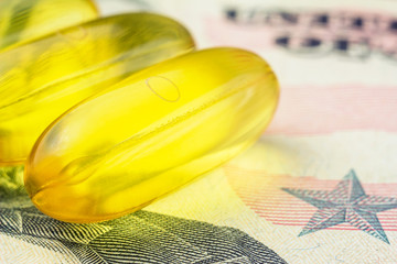 Yellow capsules omega 3, fatty acid, fish oil on dollar banknote, macro image