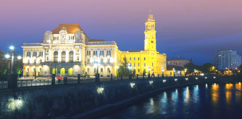 Naklejka na ściany i meble Oradea City Hall on embankment in twilight