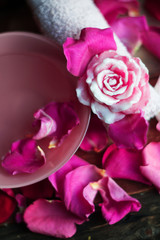 Bowl with water and rose petals on wooden table