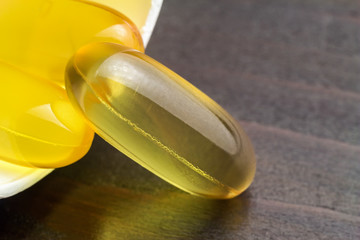 Yellow capsules omega 3, fatty acid, fish oil in bottle on wooden table, macro image