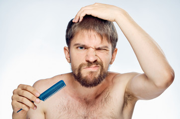 Obraz premium Man with a beard on a white isolated background holds a comb, portrait, emotions