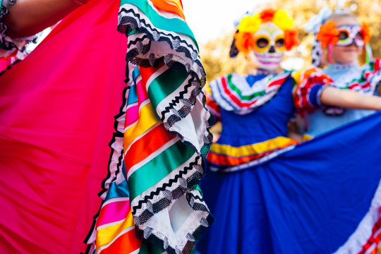Close up detail of traditional dress and blurred background of girls with masks attending Dia de los Muertos/Day of the Dead celebration