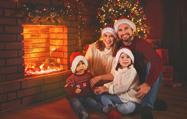 Obraz na płótnie Canvas happy family sitting by fireplace on Christmas Eve