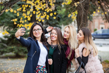 Group of four girl friends taking a selfie in the city and enjoying it