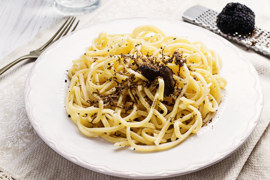 Strangozzi, italian wheat pasta with truffle on a light background.