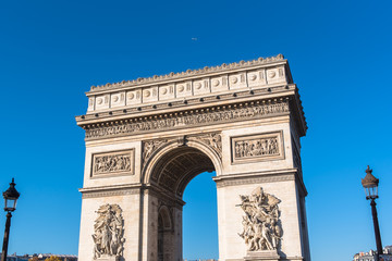 Paris, Arc de Triomphe in blue sky, beautiful monument with a plane above

