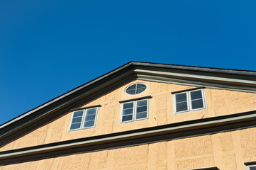 Fototapeta na wymiar Ein Haus mit orangem Giebel und einem Ortgang aus Schiefer unter strahlend blauem Himmel