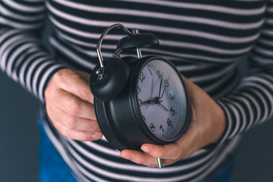 Woman winding retro alarm clock