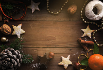 Christmas background. Cookies, sugar powder, nuts, spices, baking molds, fir-tree branch, pine cones on rustic background,  top view, copy space