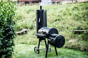 Black metal Locomotive grill with a pellet  smoker on green grass background  - 182458256
