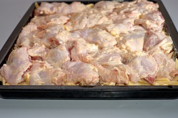 Woman at home fries chicken meat on a frying pan. The meat is not yet fried, raw