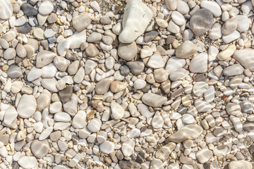 Sea pebble captured through the water on sea shore.