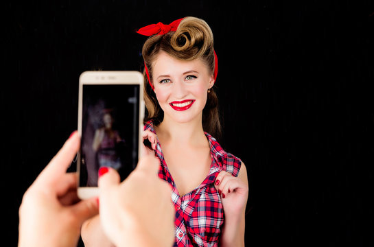 Somebody makes a photo on the phone of a girl in the style of pin-up