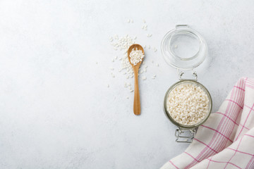 Raw  White rice variety Arborio for Italian risotto dishes in glass jar on  white concrete or stone background. Selective focus. Top view. Copy space.