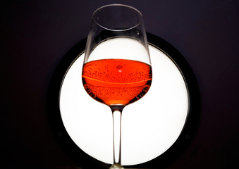 Glass of red wine in back light on black&white background.