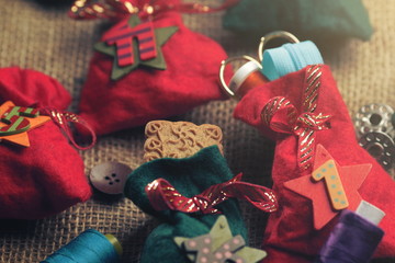 Fototapeta na wymiar part view on traditional advent calendar with small fabric bags for individual filling atatched to a rough fabric decorated with sewing accessory - bright matte light mood