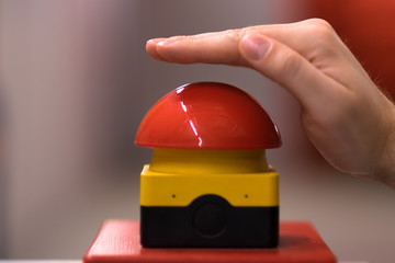 Hand above a red emergency button