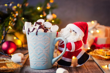 Decorative Santa Claus holding a cup of cocoa with marshmallow on the festive dark background with...