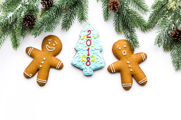 Cookies for New Year. Gingerbread man and spruce with lettering 2018 near spruce branch on white background top view copyspace