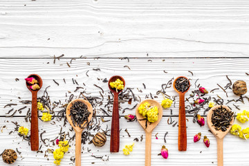 Aromatic tea. Wooden spoons with dried tea leaves, flowers and spices on white wooden background top view copyspace