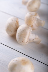 Mushrooms champignons on a white wooden background