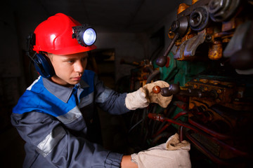 Young miner works underground in a mine with mining equipment for coal, gold, minerals.