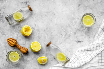 Obraz na płótnie Canvas Prepare refreshing beverage lemonade. Lemons, juicer, bottle on grey stone background top view copyspace