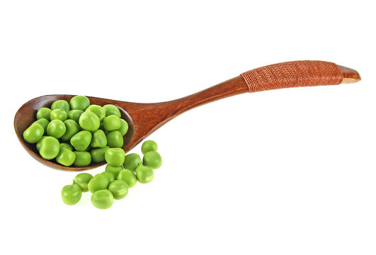 Green peas in wooden spoon on a white background