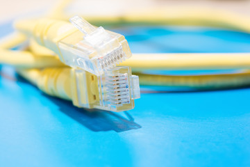 plastic connector and yellow cable type twisted pair for connection to a computer network, macro abstract background