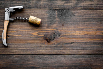 Open wine bottle. Corks and corkscrew on dark wooden background top view copyspace