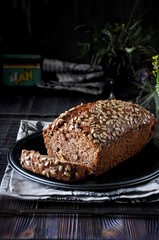 Banana cake with seeds and raisins on a metal dish and cotton napkins. Wooden table. Dark background