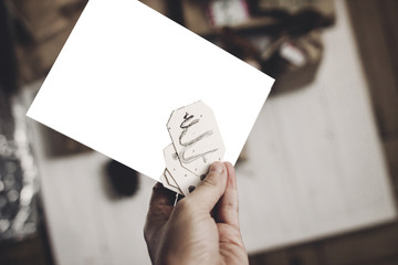 hand holding christmas card. christmas card with space for text, on white rustic wooden background...