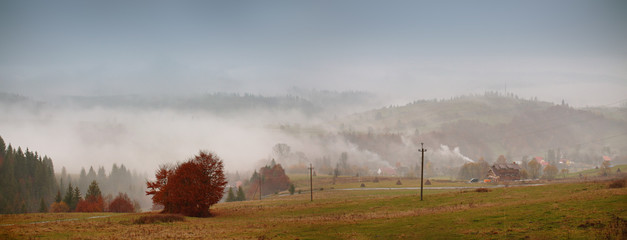 Obraz premium Autumn fog in mountain village. Cloudy rainy misty autumn