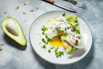 Delicious Poached Egg with Bread and Sliced Avocado on concrete background.