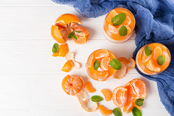 Creamy panna cotta with orange jelly in beautiful glasses, fresh ripe mandarin, blue textile on...