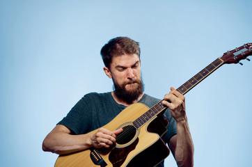 Man with a beard on a blue background playing the guitar, musical instruments, music