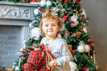 A 3 year old girl is playing in the room. Concept of Merry Christmas, New Year, holiday, winter, traditions.