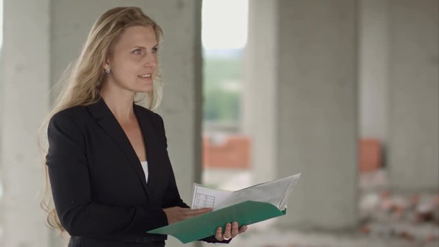 Female architect studying drafts while visiting large construction site