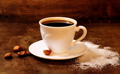 Black coffee in a white cup and saucer. Spilled sugar.