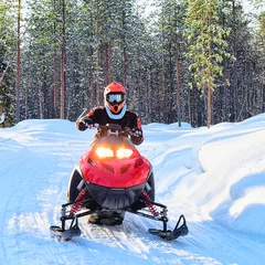 Fotobehang Woman riding red snowmobile on frozen lake at winter Rovaniemi © Roman Babakin