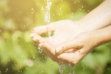Fototapeta premium Woman washing hand outdoors. Natural drinking water in the palm. Young hands with water splash, selective focus