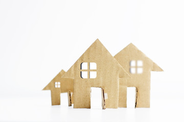 Small models of cardboard houses isolated on white background suggesting real estate project or investment