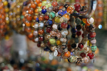 Beautiful bracelets made of murano glass hanged down in the shop window. Venice, Italy