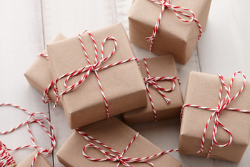 Christmas gift or present boxes wrapped in kraft paper with striped baker's twine string on white wooden background, copy space