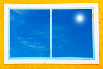 Antique wooden window frame with blue sky and sun