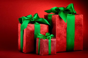 Red gift boxes with green ribbons and bow on red holiday background . Merry christmas card. Winter xmas theme.Boxing day
